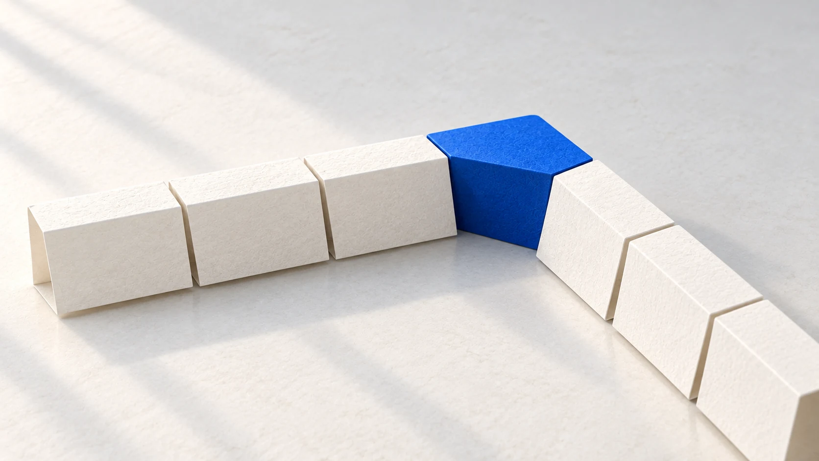 A row of white paper blocks turns at a corner formed by a fitted cobalt piece.